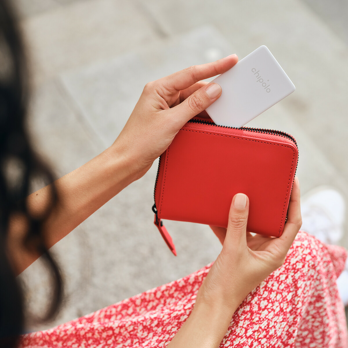 Le mani di una donna che tengono un portafoglio rosso con un dispositivo bianco.