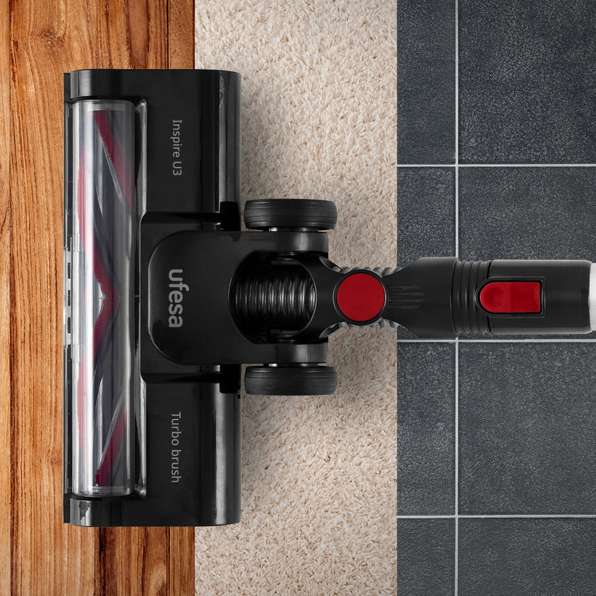 Cabezal de aspiradora con cepillo turbo. El cabezal es negro y el cepillo tiene cerdas rojas. La superficie es mitad madera, mitad alfombra.