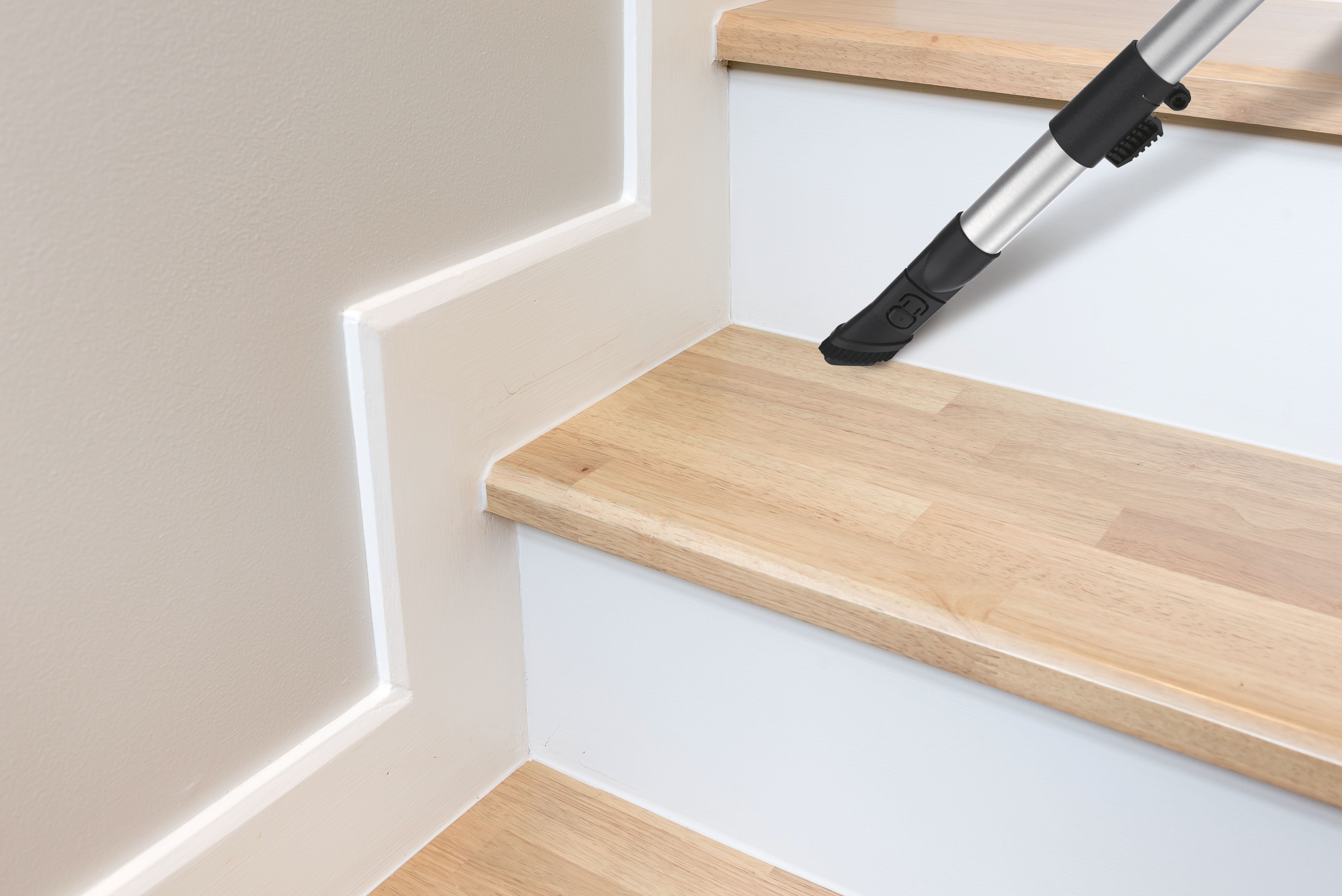 Odkurzacz jest na schodach. Stopnie są drewniane z białym wykończeniem.