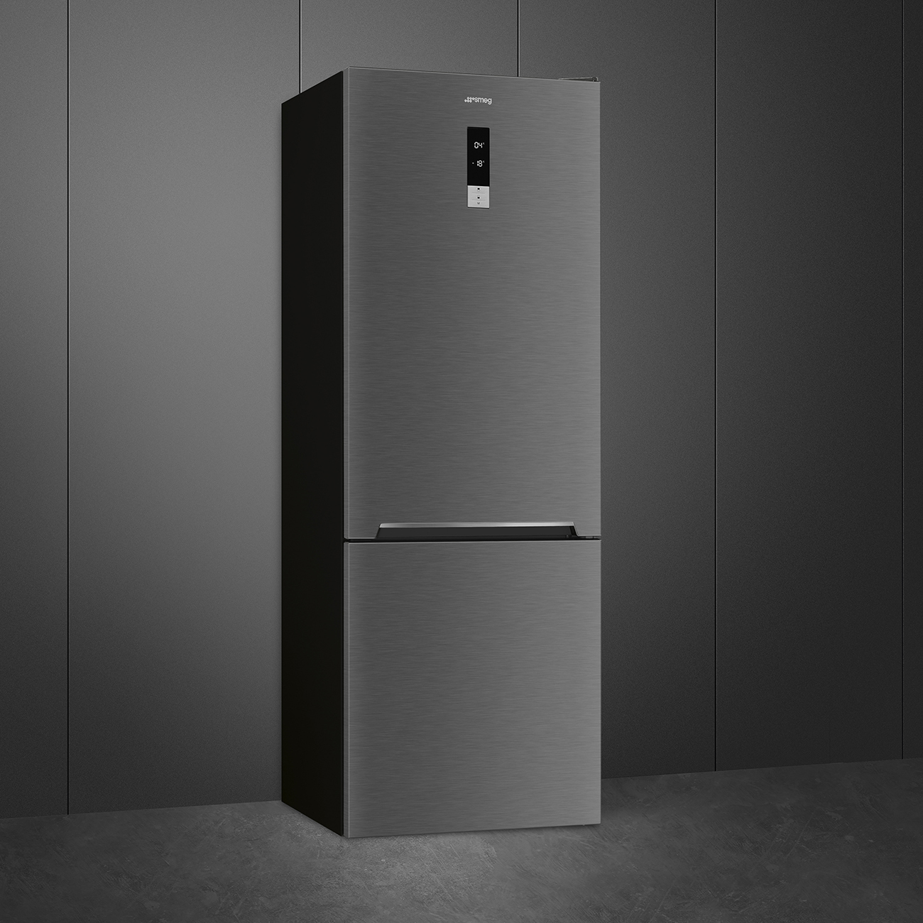 Un refrigerador gris, contra una pared gris oscuro, con acabado de metal cepillado.