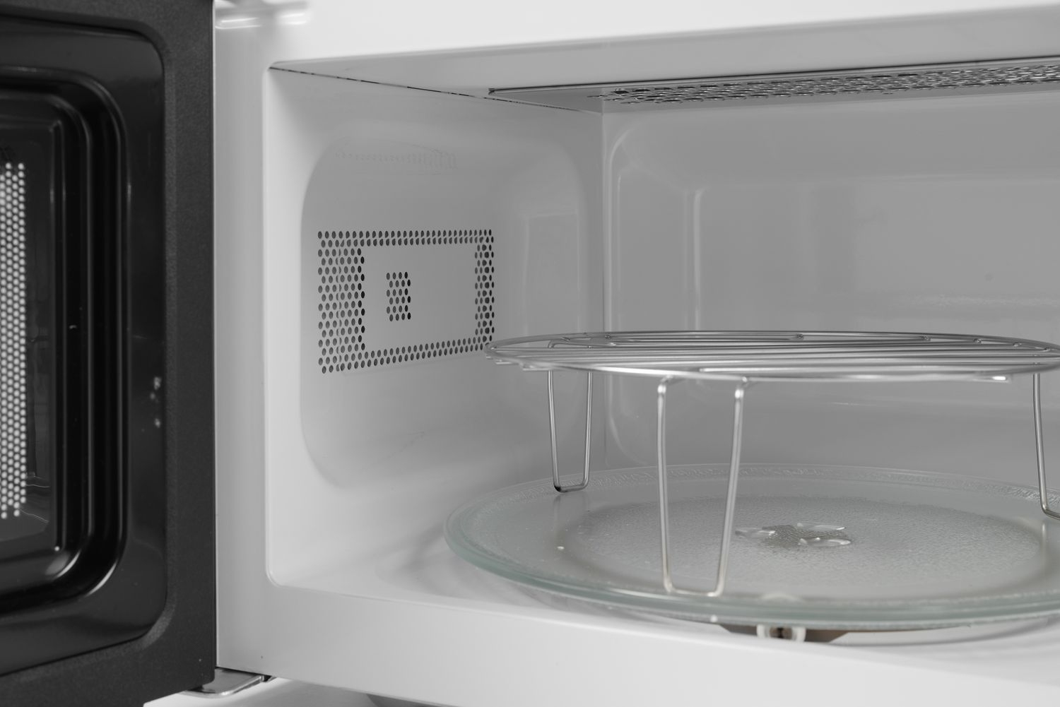 Mikrowelleninnenraum mit Glasplatte, Metallrost und Lüftung.
