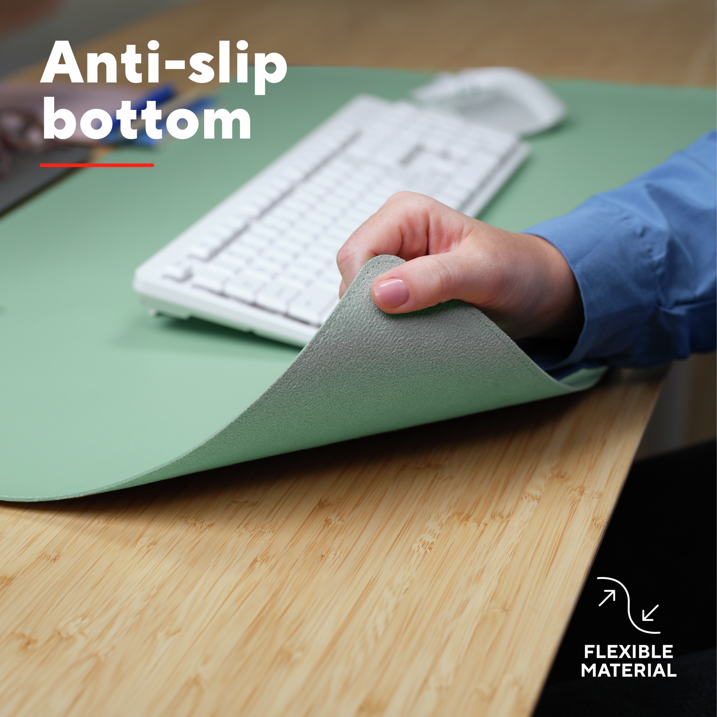 A hand lifts the corner of a green desk pad. The bottom is revealed. The desk is wood.