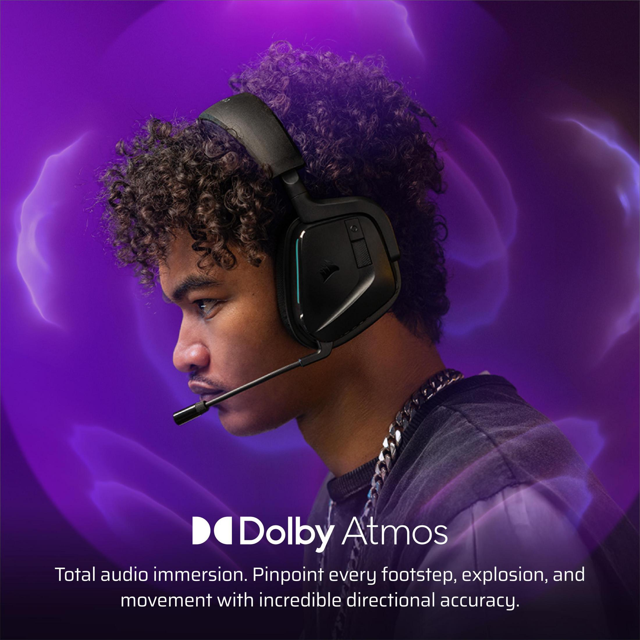 Młody mężczyzna w słuchawkach, fioletowe tło, tekst Dolby Atmos.
