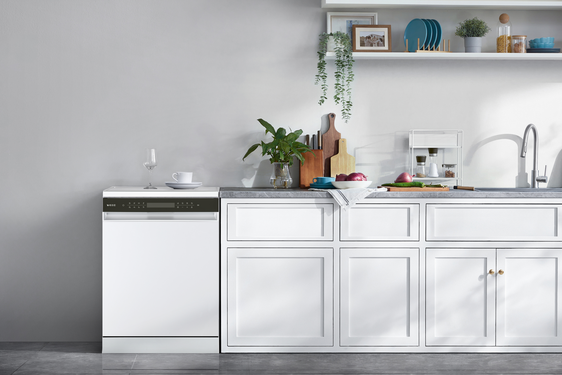 A white dishwasher with an open door is in a white kitchen. Dishes are stacked on top. Wooden floor.