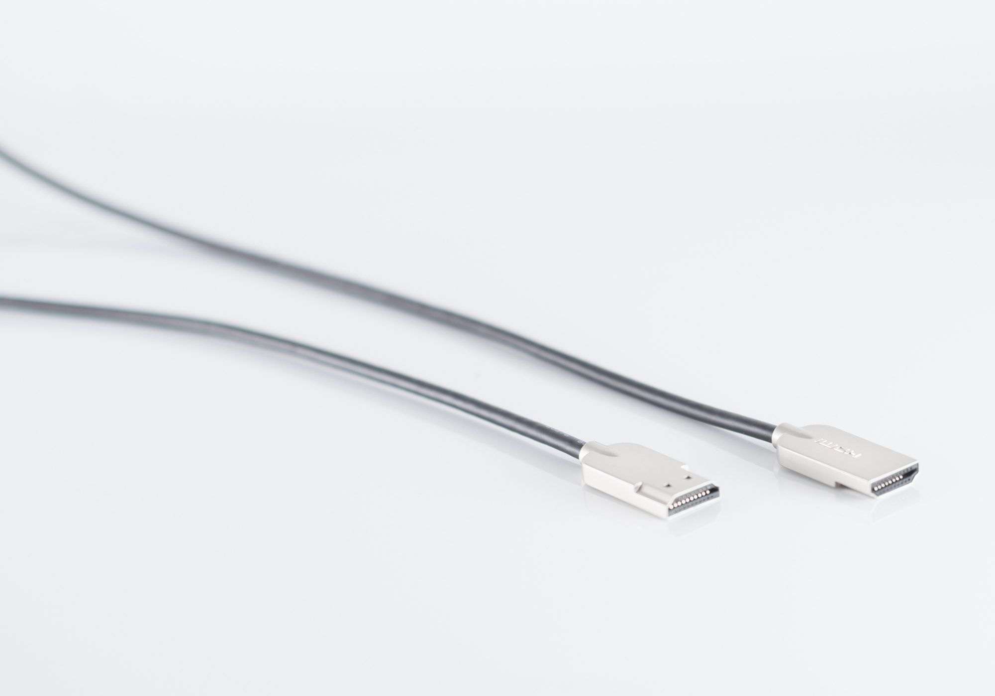 Zwei schwarze HDMI-Kabel. Kabel liegen auf einer weißen Oberfläche. Anschlüsse sind sichtbar.
