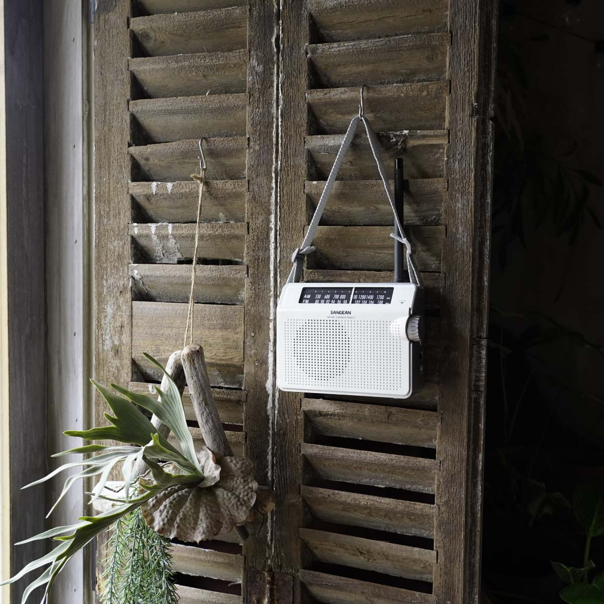 Białe radio wisi na drewnianej okiennicy.