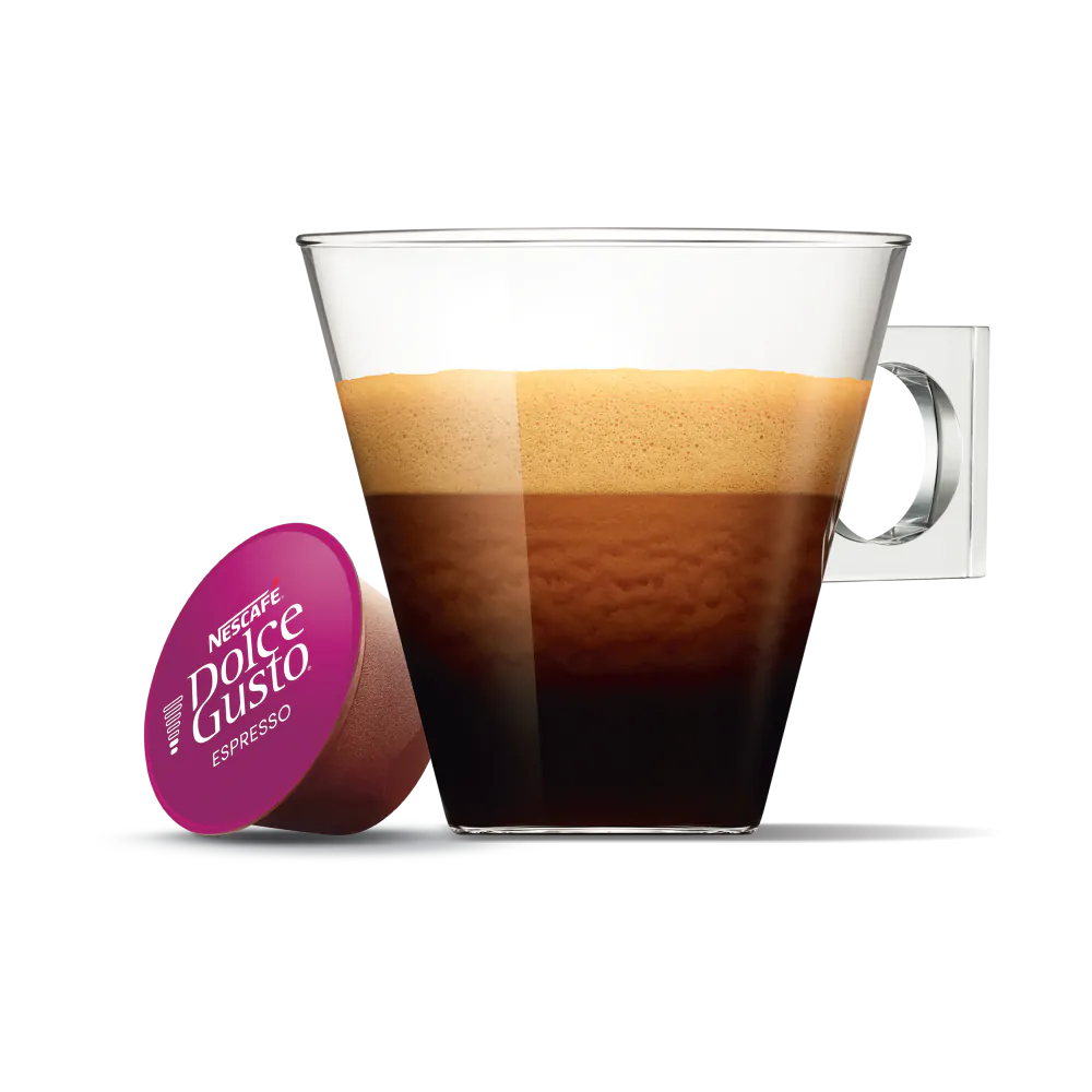 Glas mit Kaffee und Schaum, daneben eine Dolce Gusto Espresso Kapsel auf weißem Grund.