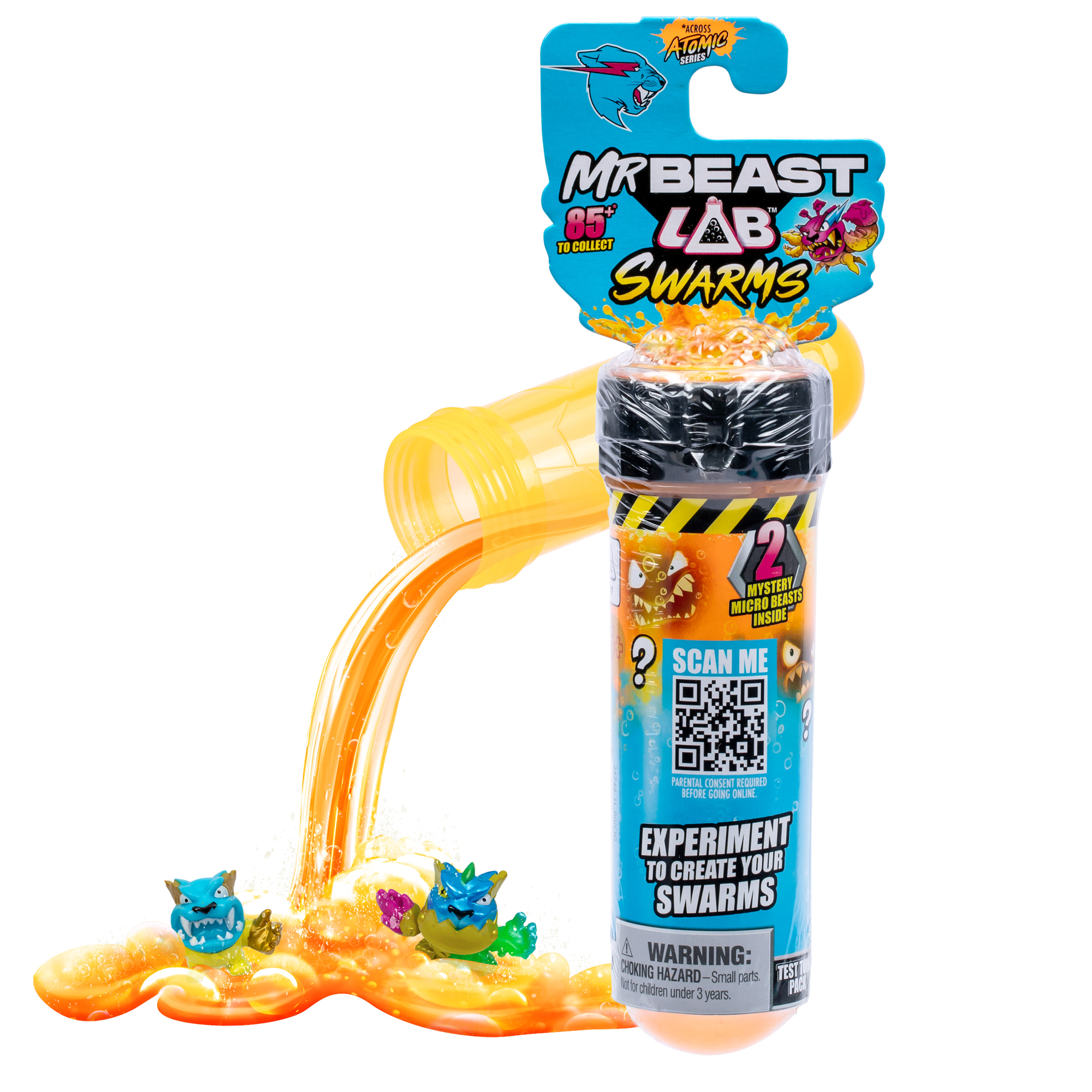 Eine transparente Röhre mit orangener Flüssigkeit und Spielzeugmonstern, die herausfließen. Die Verpackung ist blau und gelb. QR-Code vorhanden.