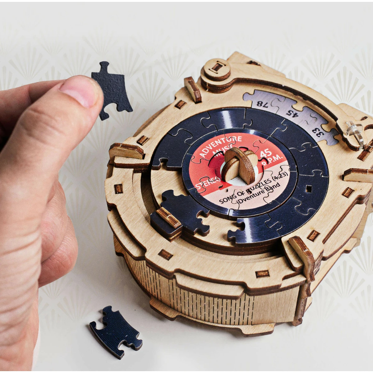 Un carillon in legno con un disco puzzle. Una mano tiene un pezzo del puzzle.