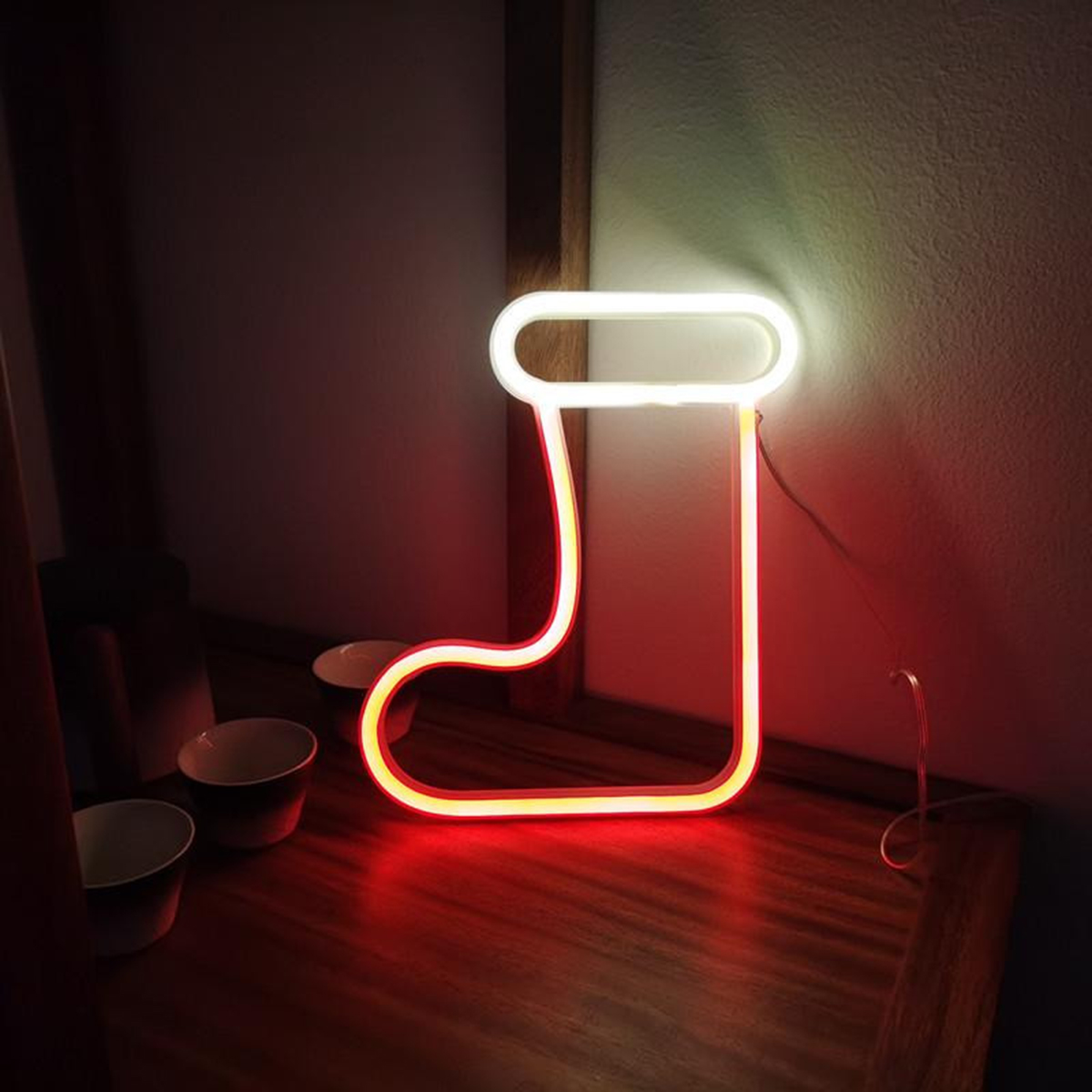 Eine neonbeleuchtete Weihnachtsstrumpf-Lampe. Das Licht ist unten rot und oben weiß.