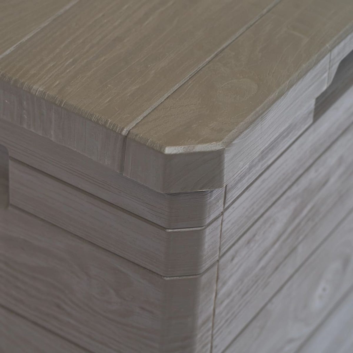 Eckdetail einer grauen Aufbewahrungsbox, Holzmaserung.