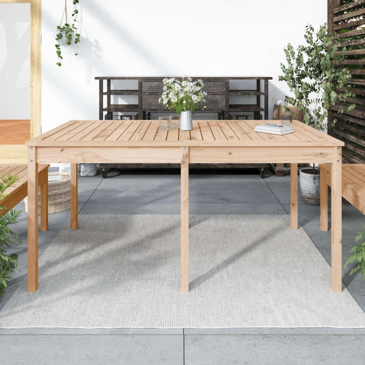 Ein Holztisch mit einem grauen Teppich. Eine Vase mit Blumen und Gläsern stehen darauf.