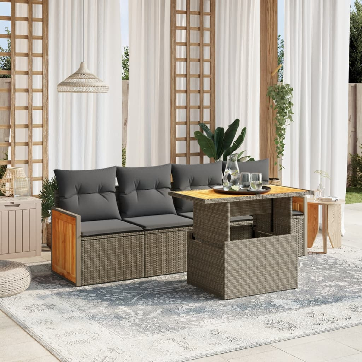 Wohnzimmer-Setup im Freien mit grauem Sofa, Couchtisch und Teppich. Vorhänge und Pflanzen im Hintergrund.