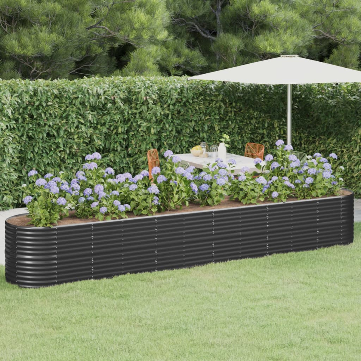 Schwarzes Hochbeet mit Blumen und einem Tisch im Hintergrund.