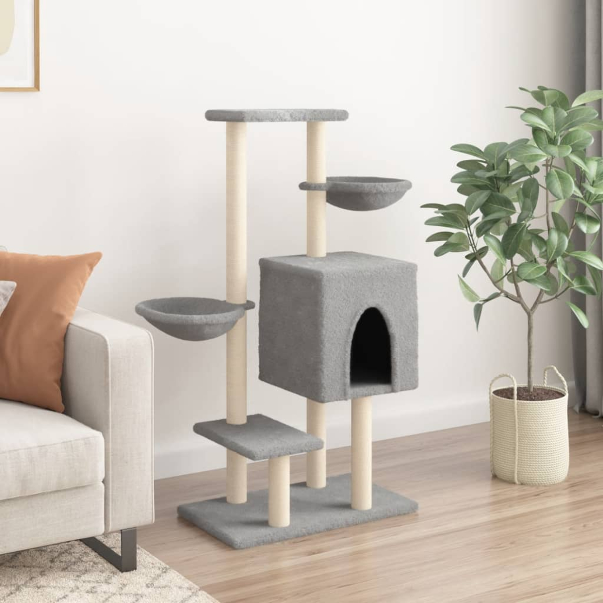 Ein grauer Katzenturm in einem Wohnzimmer mit Couch, Pflanze und weißer Wand.