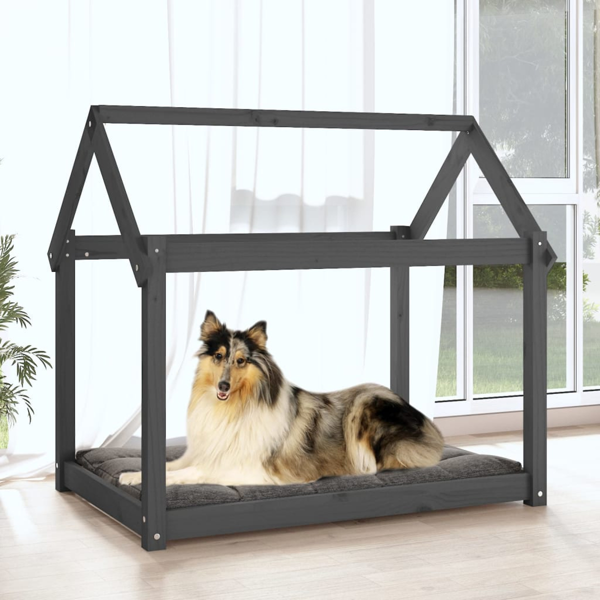 Ein Hund liegt in einem grauen Hunde-Bettrahmen aus Holz, hausförmig, mit Hintergrund.