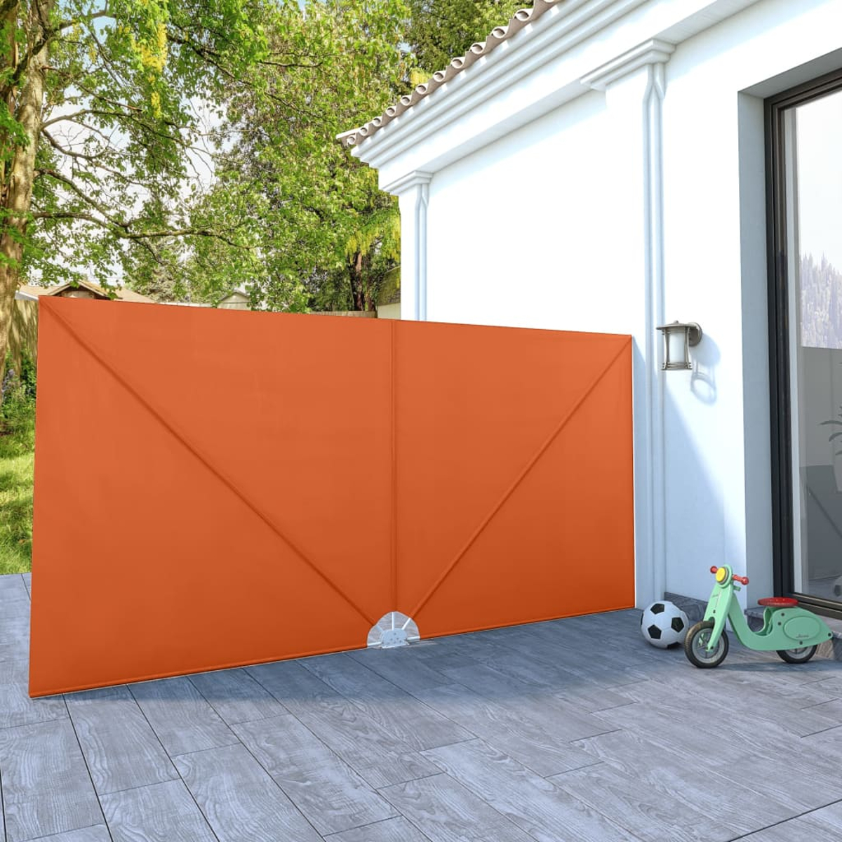Orangene Markise, vor einer weißen Wand und einer grauen Terrasse. Ein grüner Roller und Ball sind da.