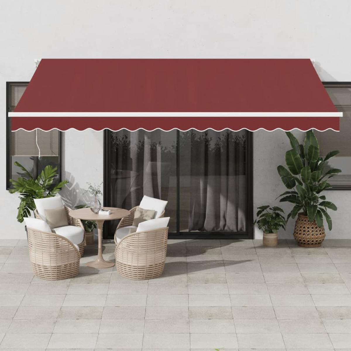Eine Terrasse mit Korbstühlen, einem runden Tisch und einer roten Markise. Pflanzen und eine Glastür sind sichtbar.