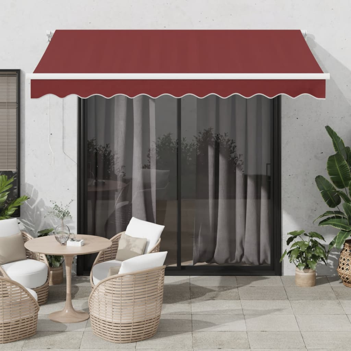 Eine weinrote Markise bedeckt eine Terrassengarnitur. Eine Topfpflanze steht auf der Terrasse.