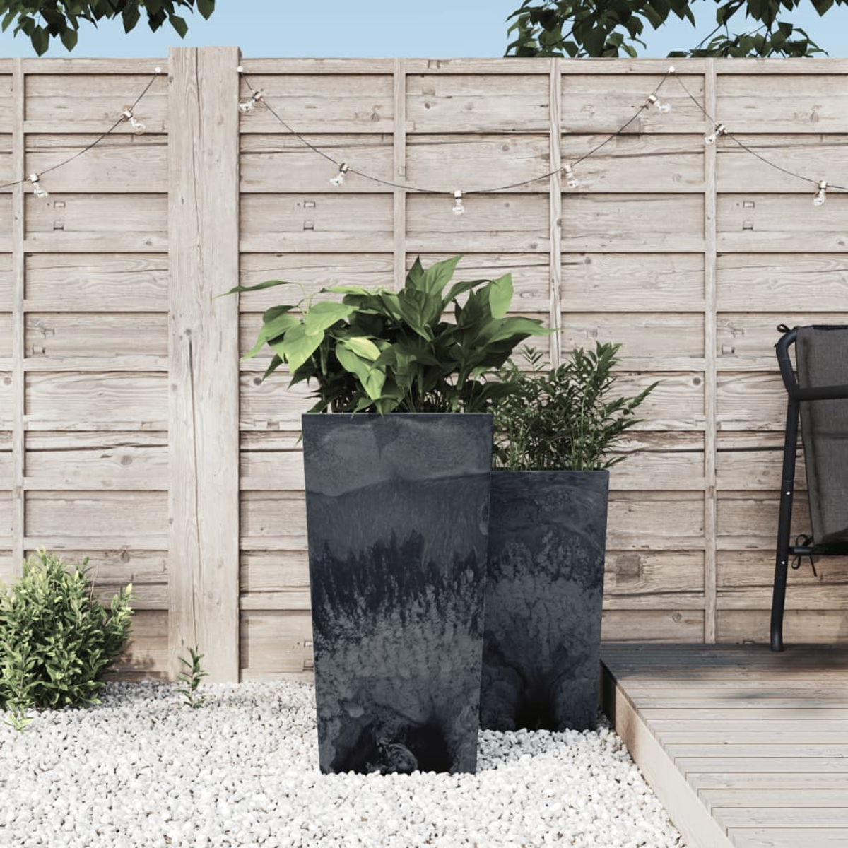 Zwei schwarze Pflanzgefäße mit Pflanzen in einer Gartenszene. Holzzaun und Deck im Hintergrund.