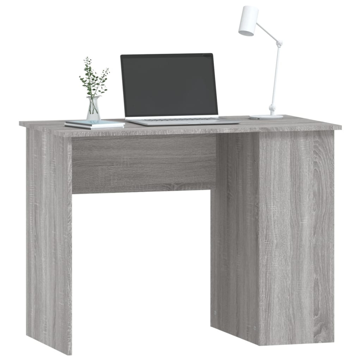 Ein grauer Schreibtisch mit Laptop, Lampe und kleiner Pflanze. Hintergrund: weiße Wand.