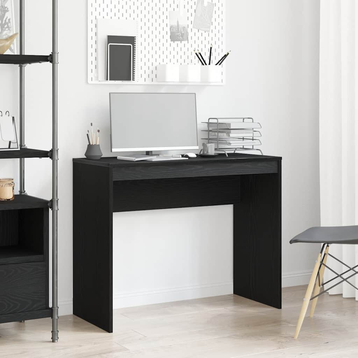 Schwarzer Schreibtisch mit Computer, Zubehör und Lochwand. Der Schreibtisch ist schwarz und schlicht.
