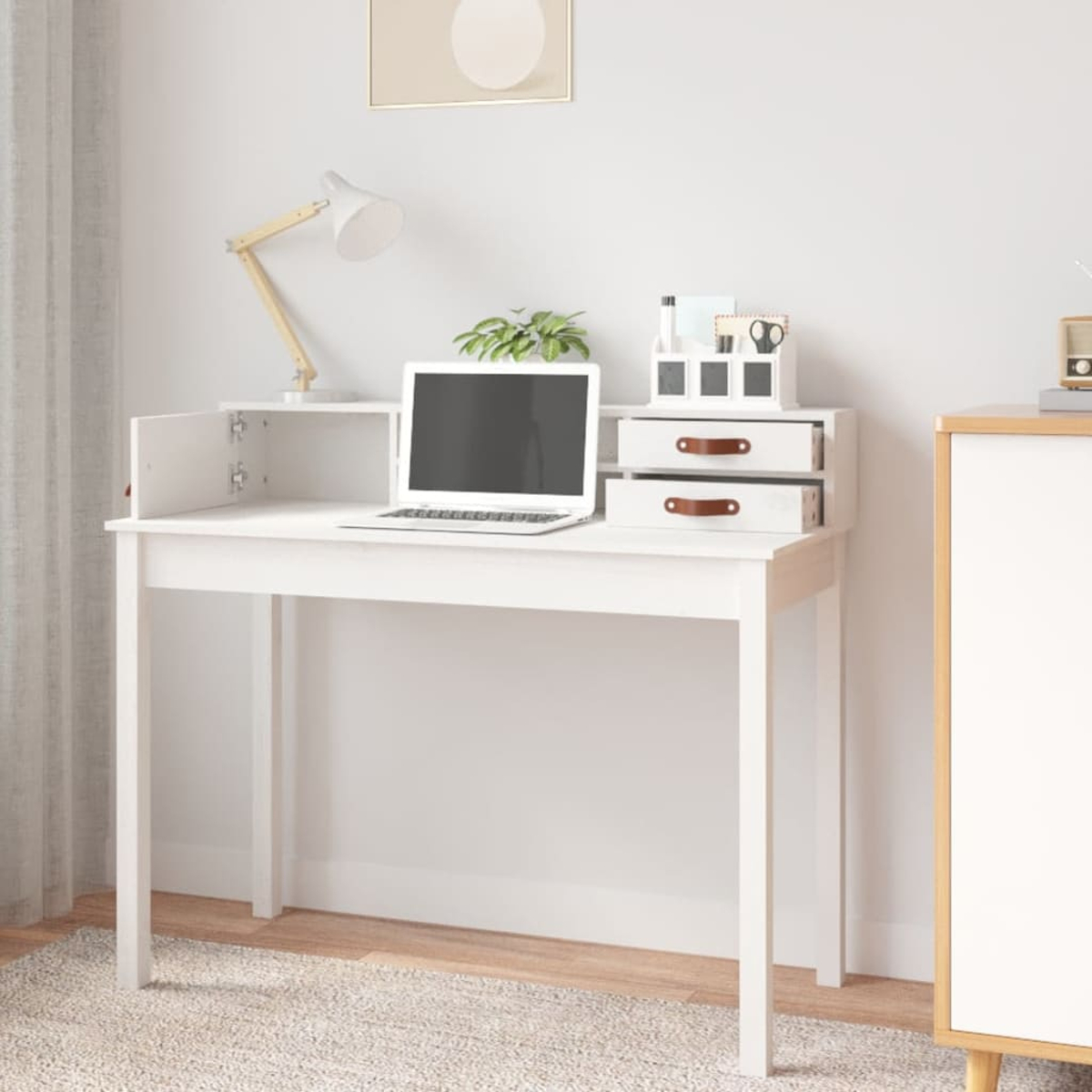 Weißer Schreibtisch mit Laptop, Lampe und Zubehör. Hintergrund: Wand und Schrank.