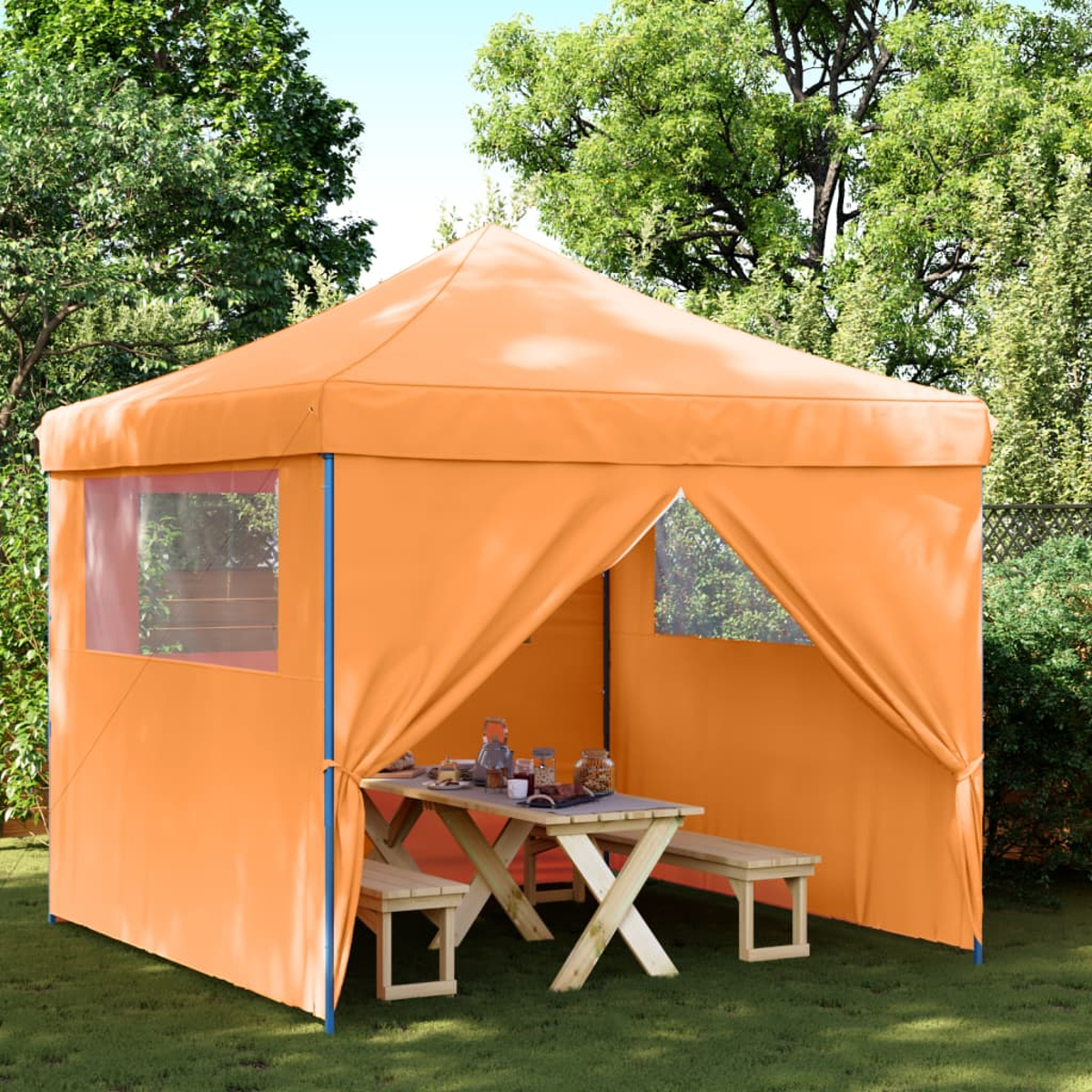 Orangener Zelt in einem Garten mit Tisch und Bänken. Grüne Bäume im Hintergrund.