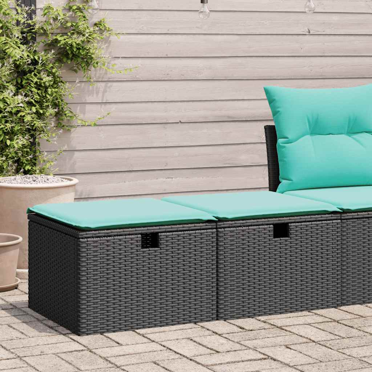 Panca contenitore in vimini grigio scuro con cuscini verde acqua, su un patio.
