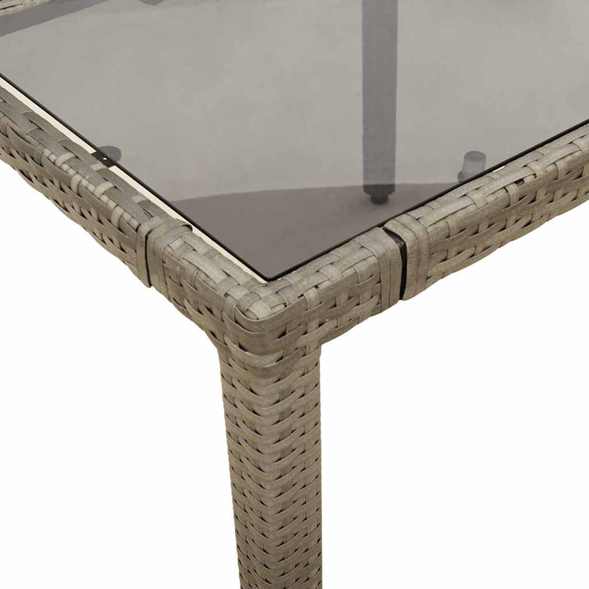 Primo piano di un angolo di tavolo in vetro. Struttura in rattan grigio, sfondo bianco.