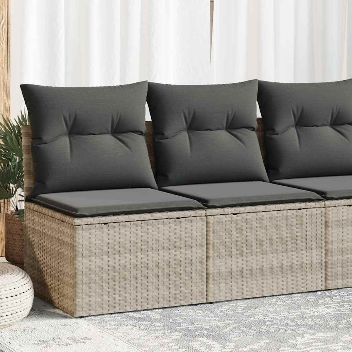 Beiges Rattansofa mit drei grauen Kissen nah.