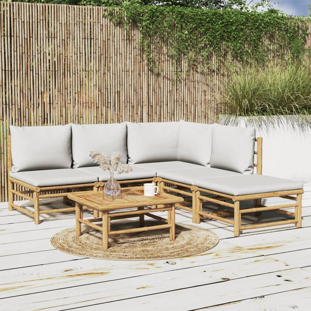 Outdoor-Bambus-Sitzgruppe mit weißen Kissen und kleinem Tisch auf Holzterrasse.