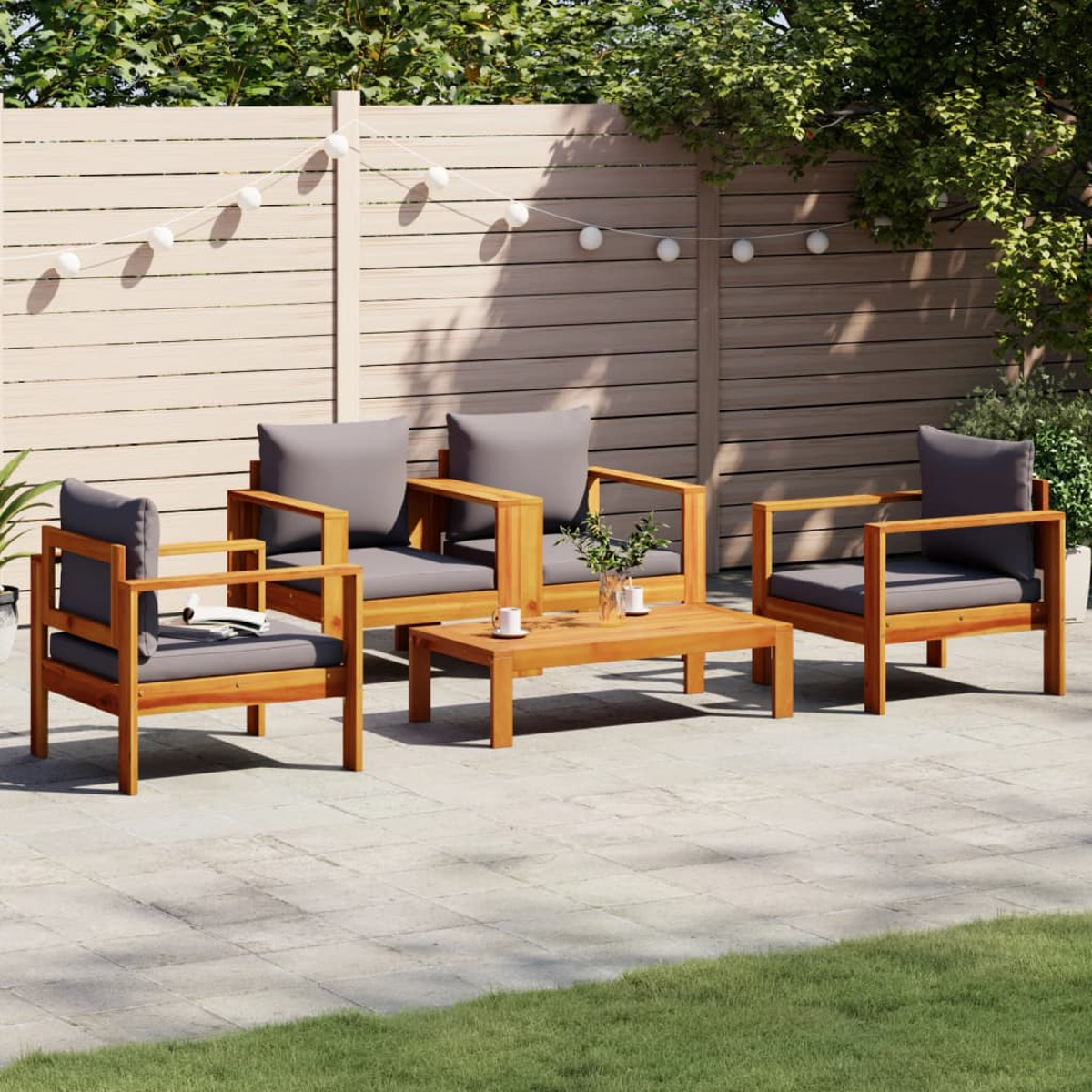 Gartenmöbel-Set aus Holz. Enthält Stühle mit grauen Kissen und einen Couchtisch auf einer Steinterrasse.