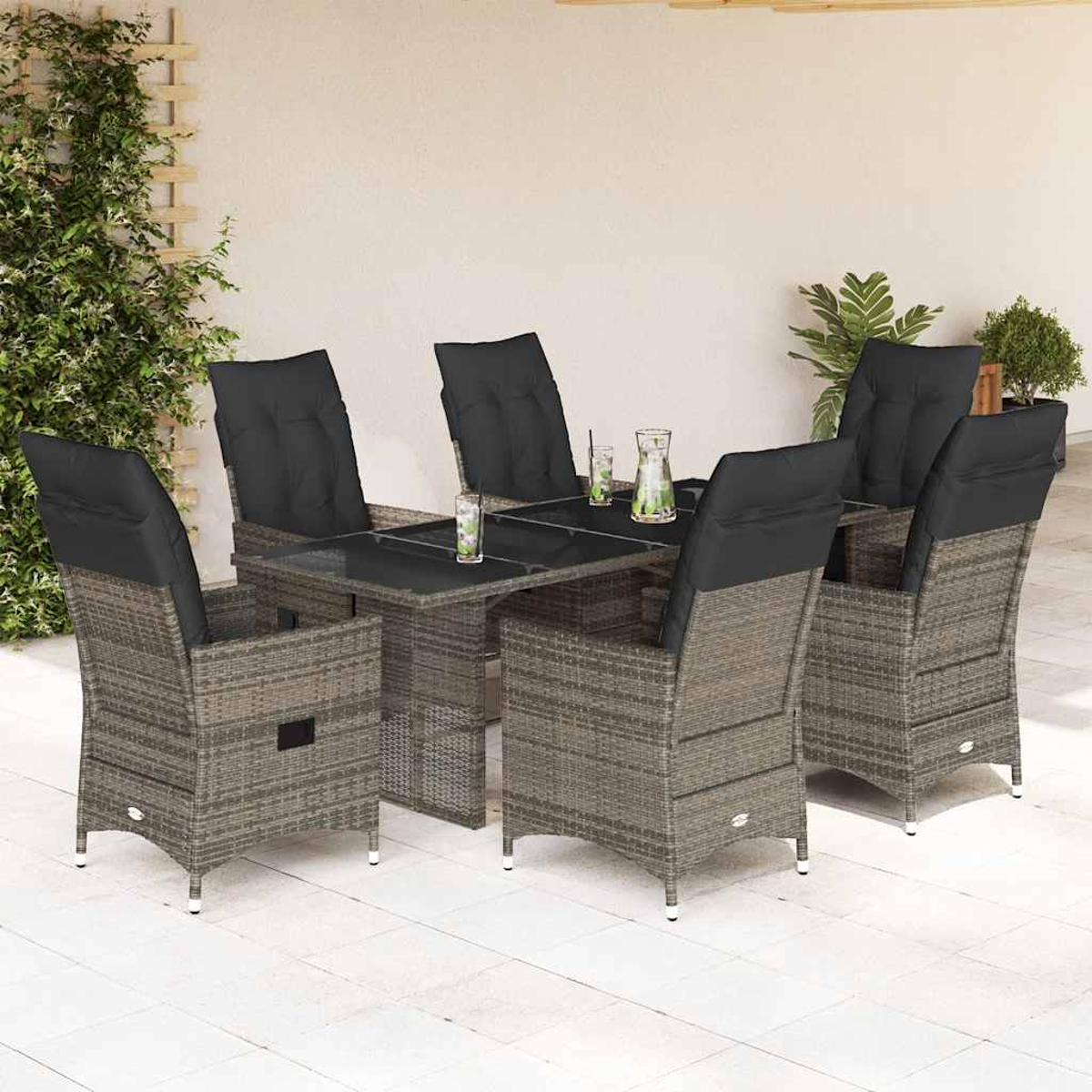 Set da pranzo all'aperto: tavolo in rattan, sei sedie con cuscini neri, bevande. Muro beige e pavimento piastrellato. Giorno soleggiato.
