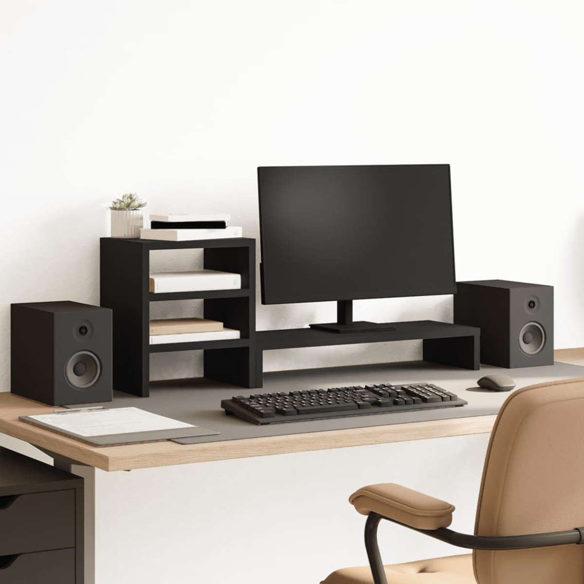 Ein Schreibtisch mit Monitor, Lautsprechern, Tastatur und Maus. Es gibt eine Pflanze.
