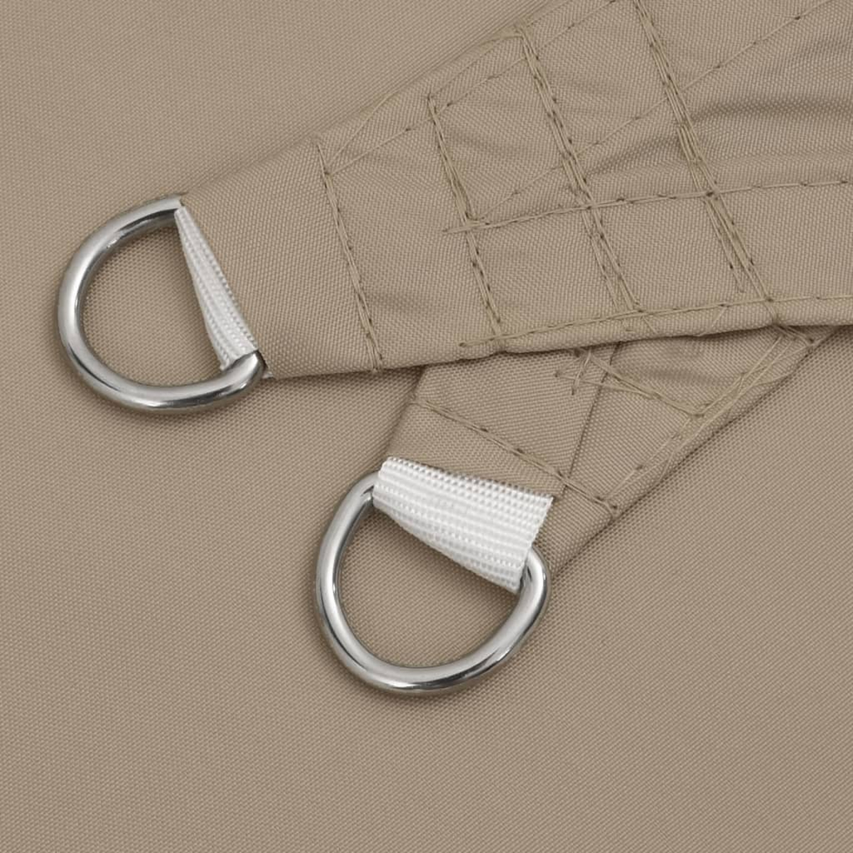 Nahaufnahme von beigem Stoff mit angebrachten Metall-D-Ringen.