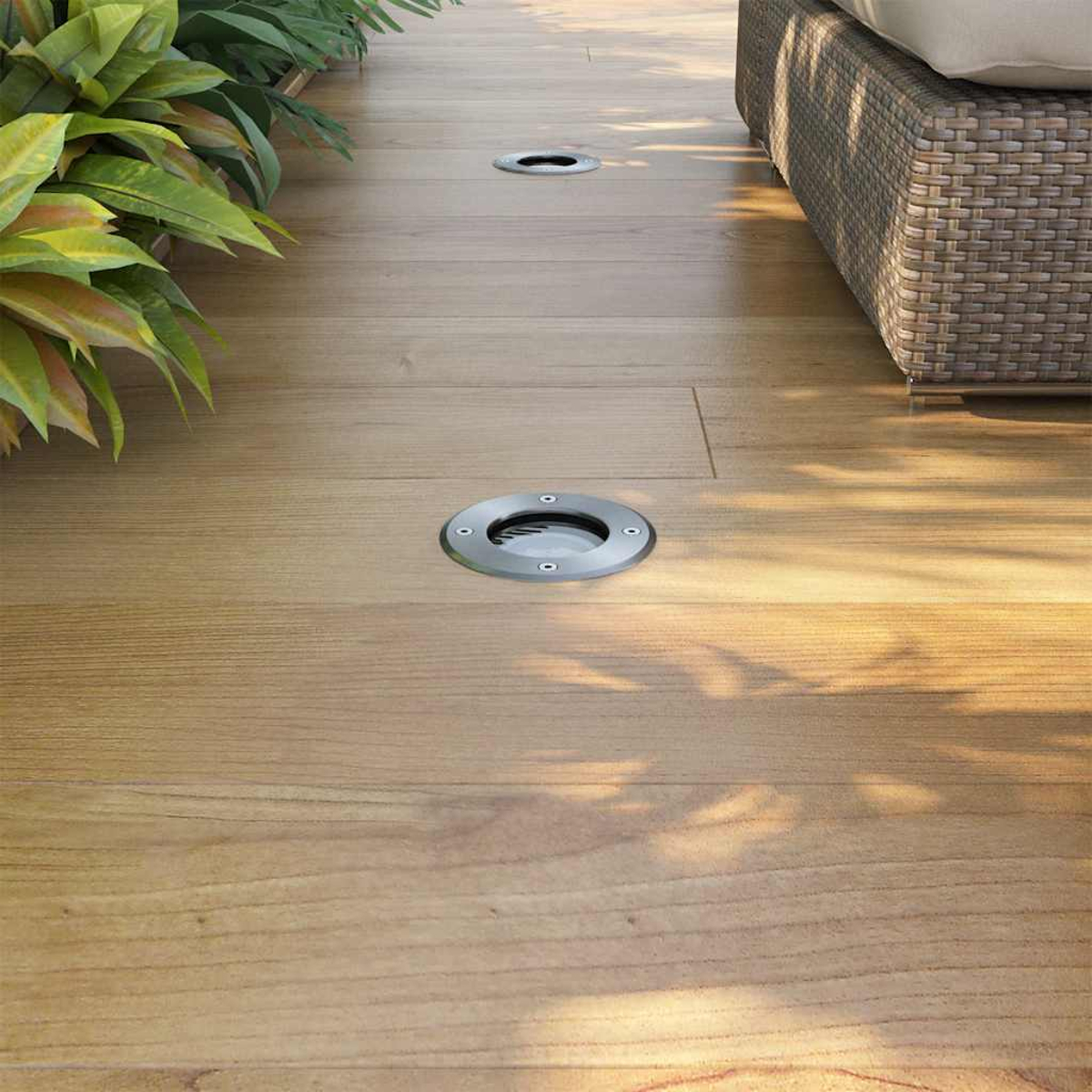 Pavimentazione in legno con luci esterne. Una sedia in vimini e piante.