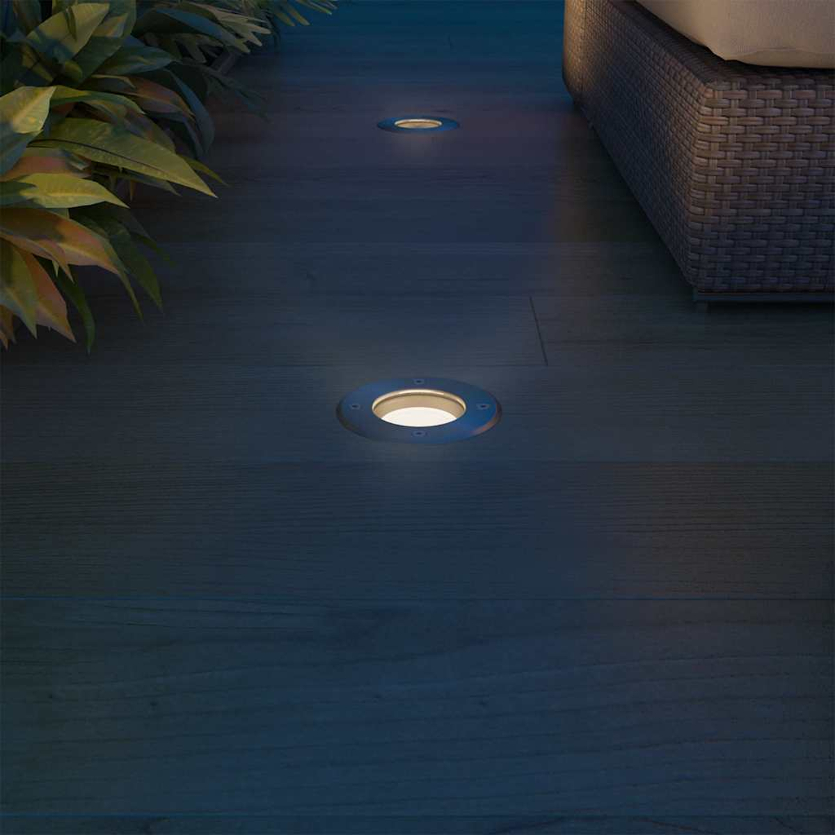 Terrazza con luci incassate. Sullo sfondo un divano intrecciato.