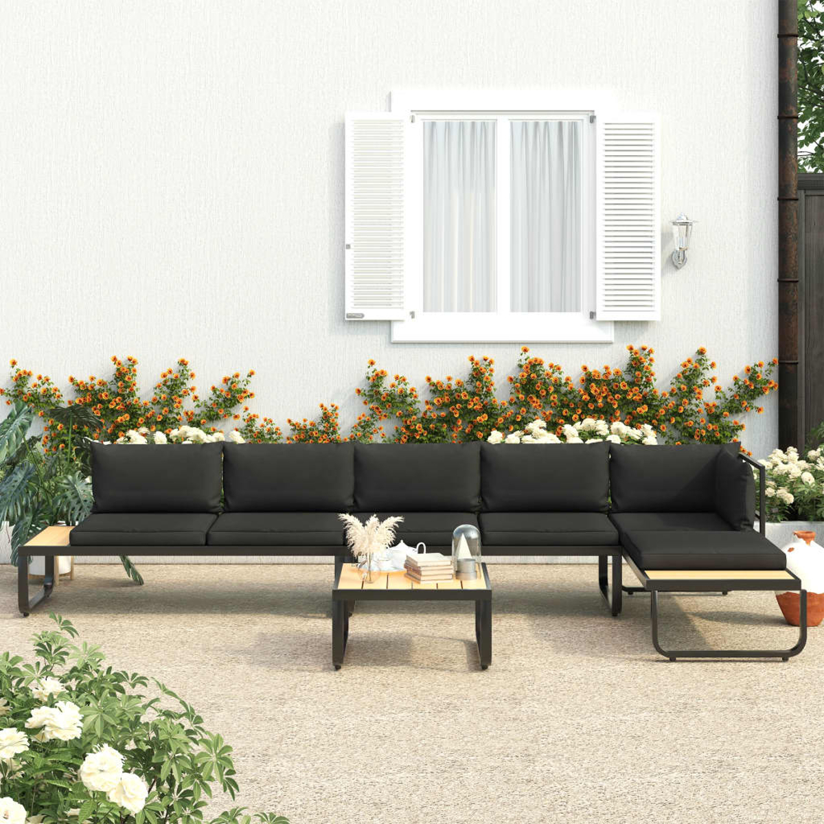 Outdoor-Sofagarnitur mit Tisch, Blumen und weißem Gebäude im Hintergrund.