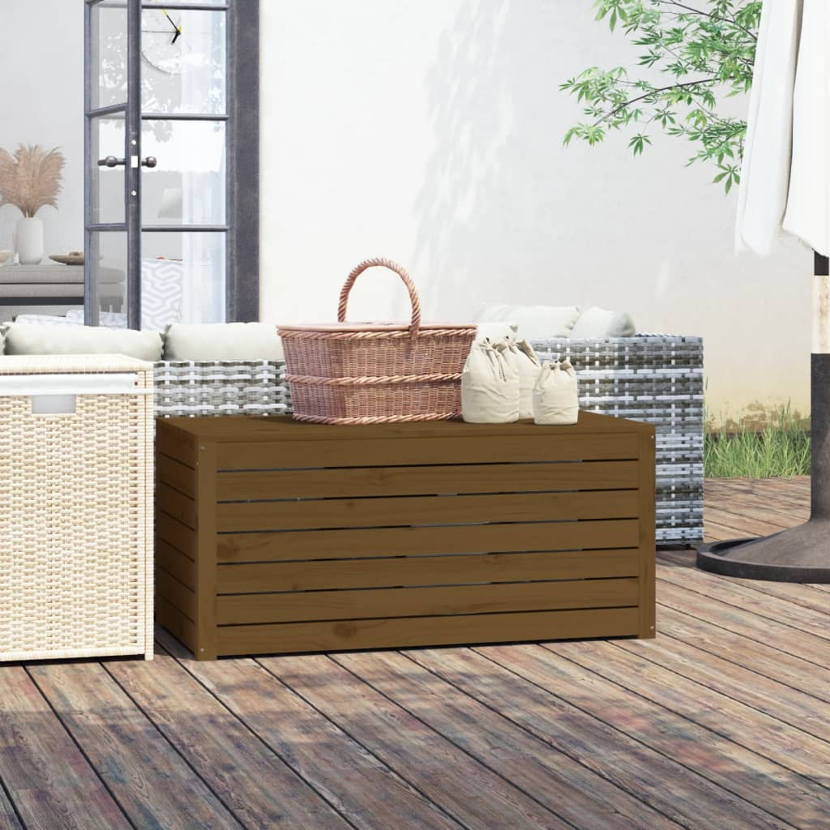 Holzkiste auf Deck. Korb, Taschen oben. Weiße Wand, Pflanzen und Sitzgelegenheiten im Hintergrund.