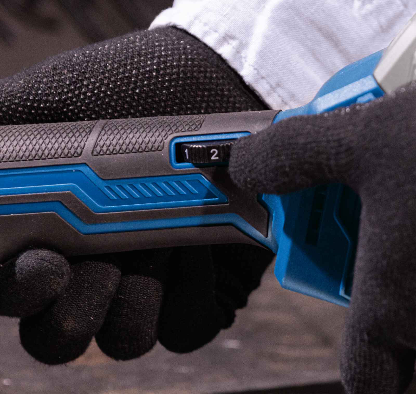 Close-up van een hand die een gereedschap bedient, met een instelknop '1' en '2'.