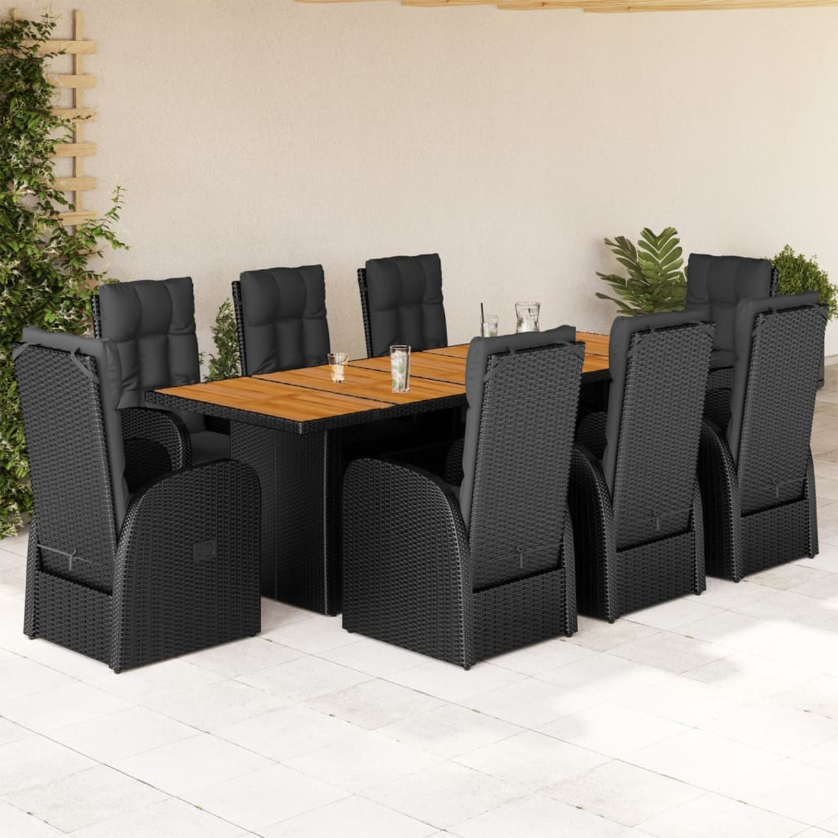 Set da pranzo all'aperto: sedie e tavolo in vimini nero. Tavolo con piano in legno. Sfondo muro.