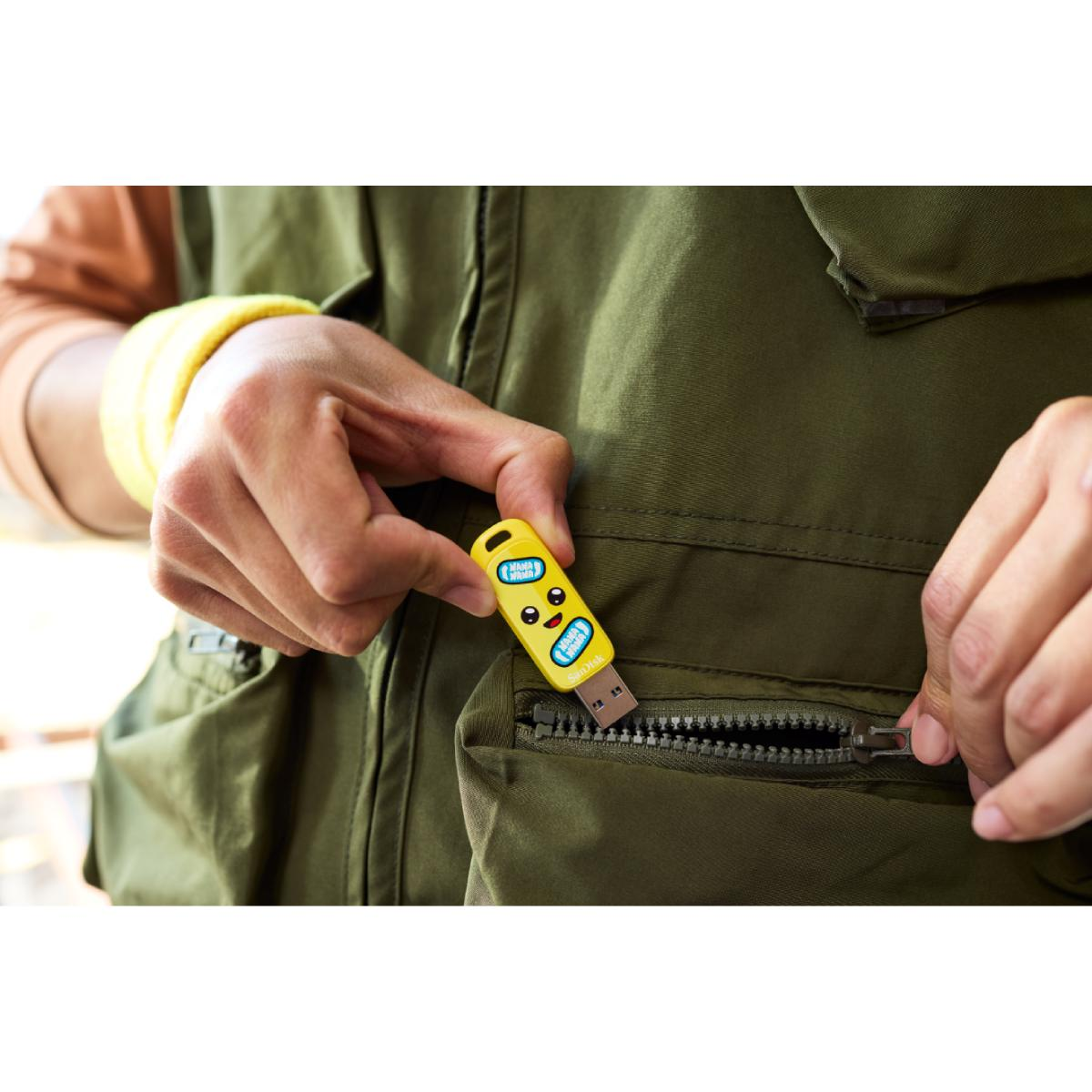 Ręka wkładająca żółty pendrive do kieszeni.