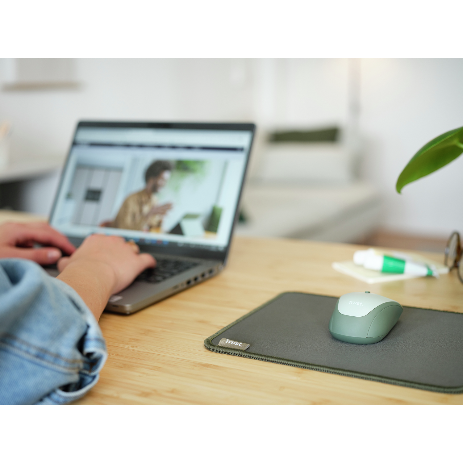 Gros plan d'un bureau avec un ordinateur portable, une souris et un tapis de souris vert.