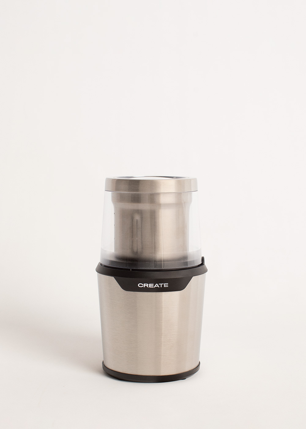 Molinillo de café plateado y negro. Cuerpo plateado con tapa transparente. Logotipo CREATE al frente.