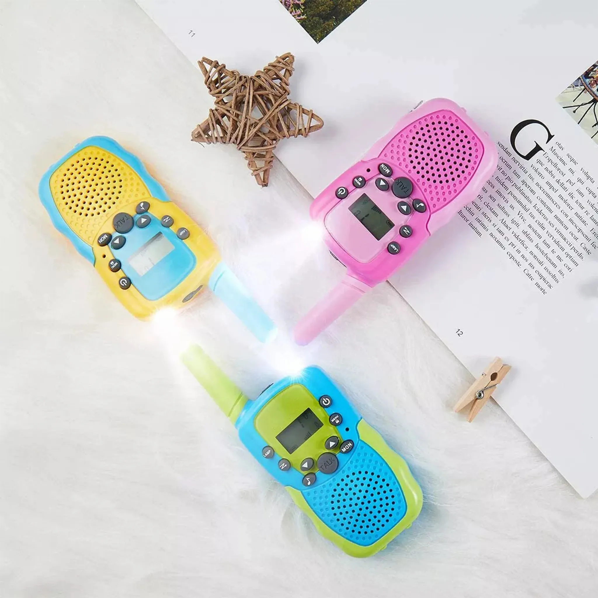 Drei Walkie-Talkies mit eingeschalteten Lichtern, neben einem Stern und einer Wäscheklammer.