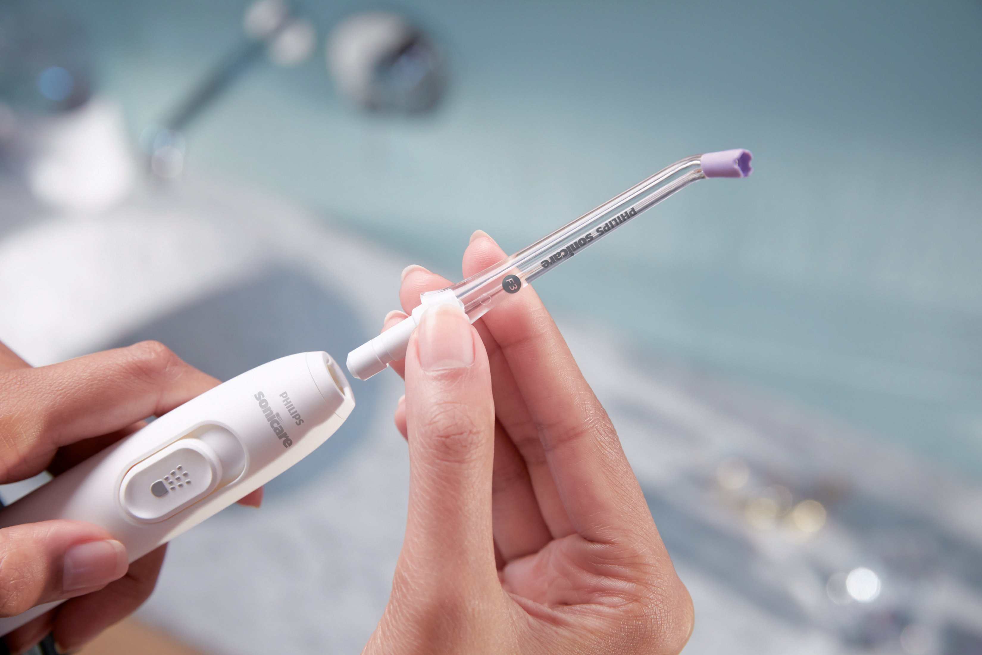 Bir kişinin elleri Philips Sonicare su ipi başlığını birleştiriyor.