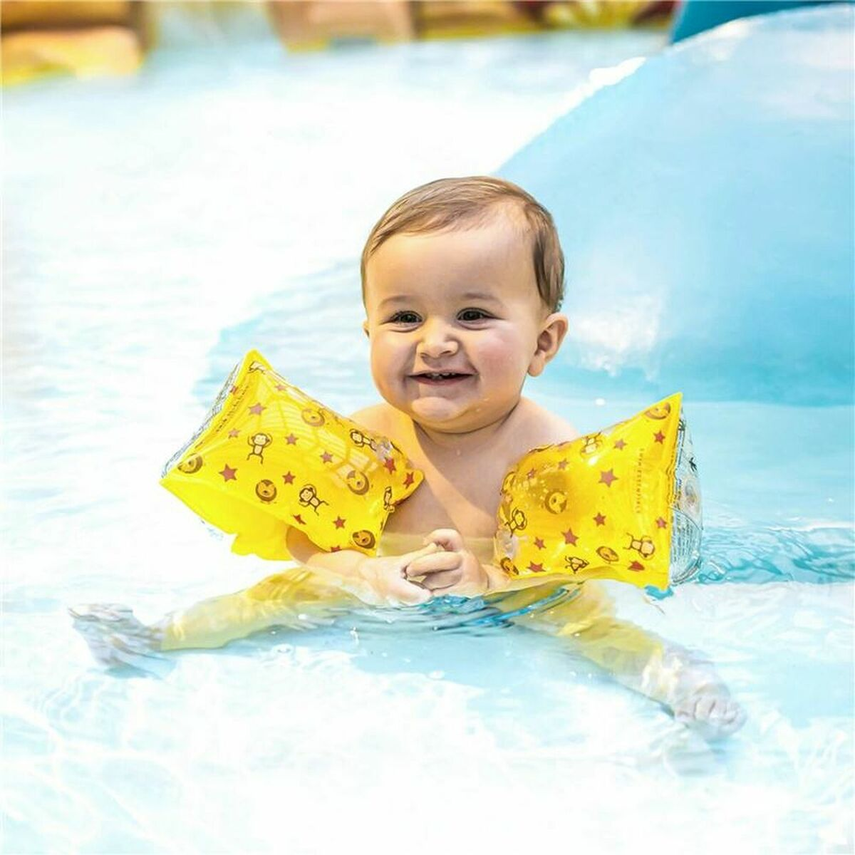 Ein Baby im Wasser mit gelben Armbändern mit Affen- und Löwenmotiven.