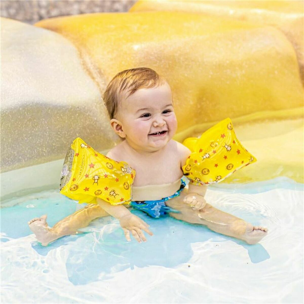 Baby in einem Pool, trägt gelbe Armbänder mit Affen- und Löwendesigns.