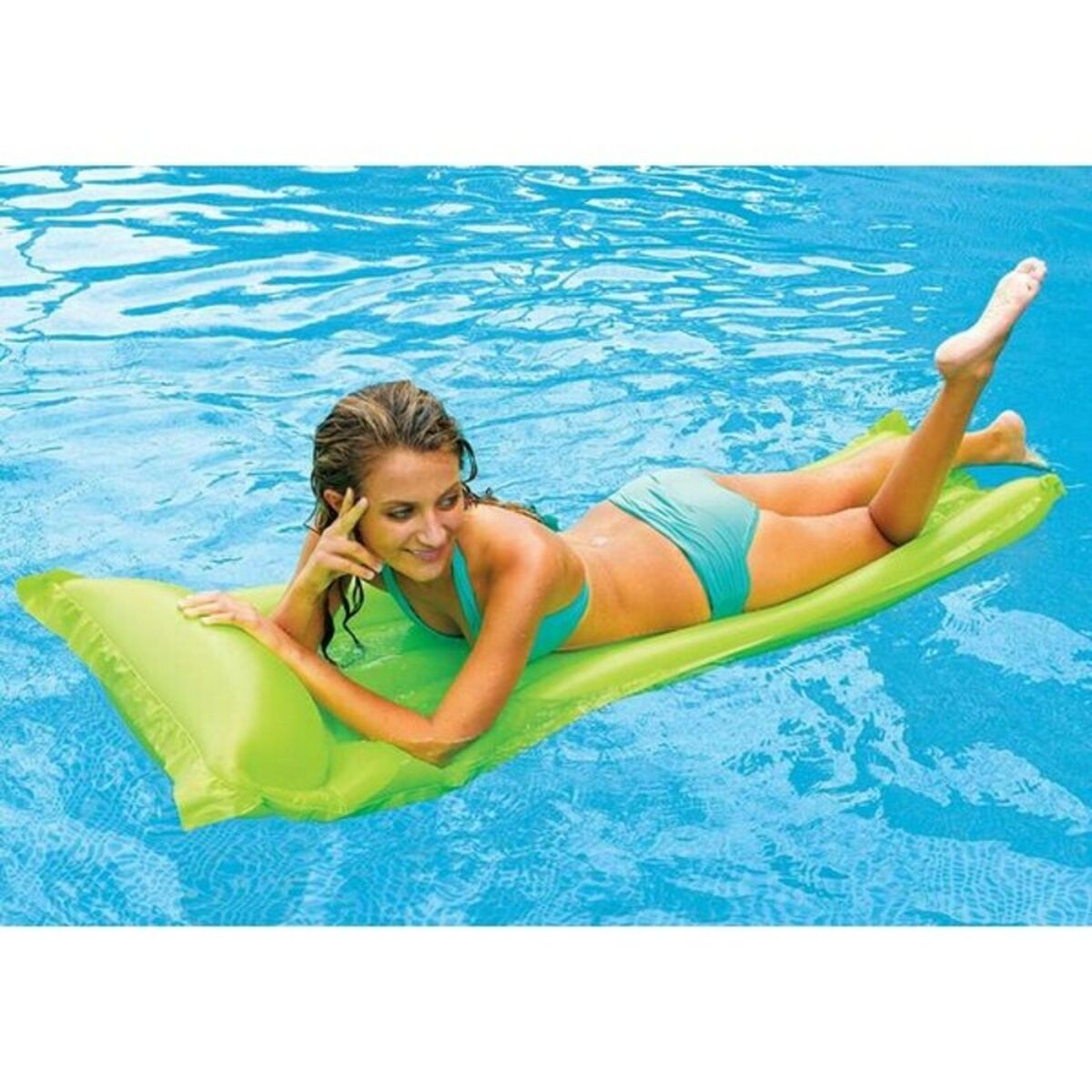 Eine Frau auf einem grünen aufblasbaren Floß in einem Swimmingpool. Sie trägt einen blauen Bikini.